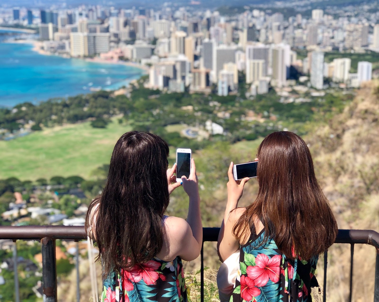 Two millennials matching outfits Tourists Taking photos of Waikiki at the top of diamond head hike